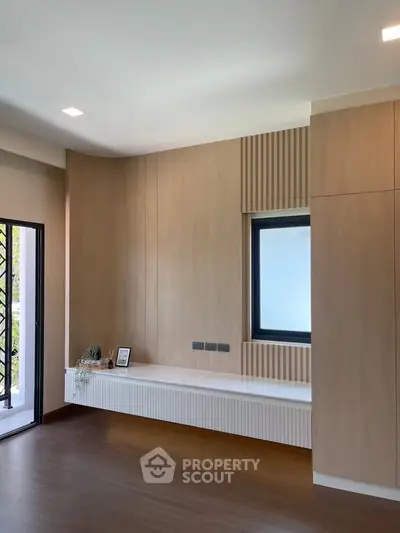 Modern living room with wooden paneling and large window, offering a sleek and minimalist design.