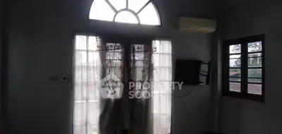Spacious living room with large window and natural light, featuring air conditioning and wall-mounted TV.