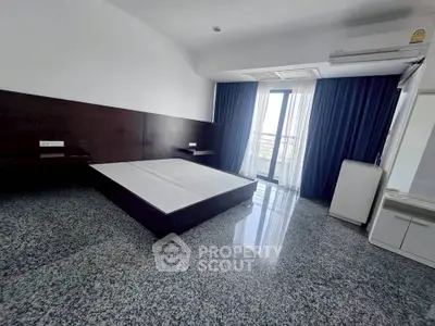 Spacious bedroom with modern design and large window offering natural light.