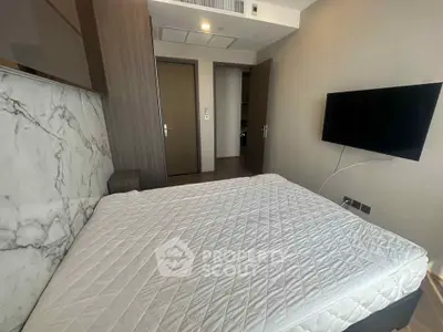 Modern bedroom with marble accent wall and mounted TV, showcasing sleek design.