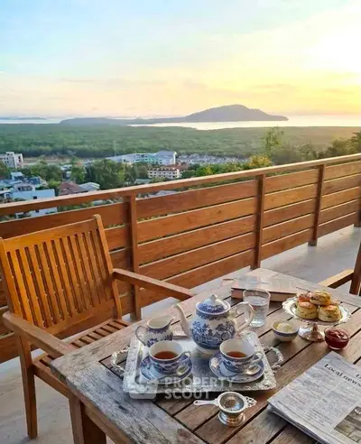 Stunning balcony view with elegant tea setup overlooking scenic landscape and sunset.