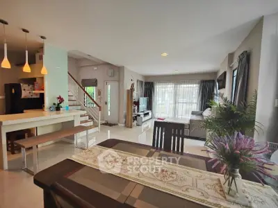 Spacious open-plan living room with modern kitchen and dining area, featuring elegant decor and ample natural light.