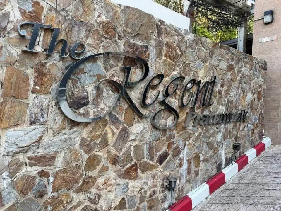 Elegant stone wall with stylish signage at The Regent, showcasing luxury real estate entrance.