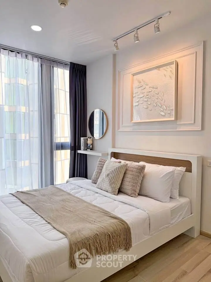 Modern bedroom with stylish decor and natural light, featuring a cozy bed and elegant wall art.
