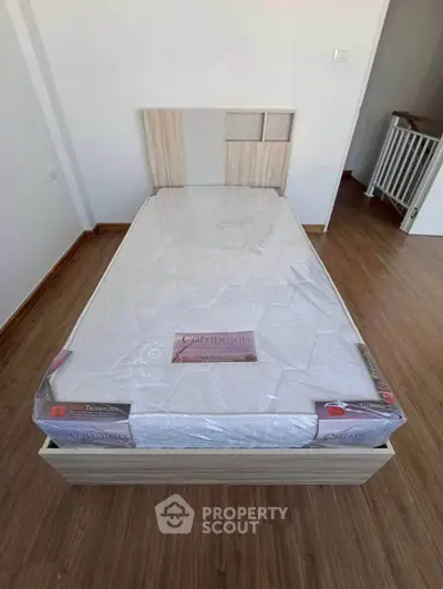 Modern bedroom with sleek wooden flooring and a stylish single bed frame, perfect for cozy living.