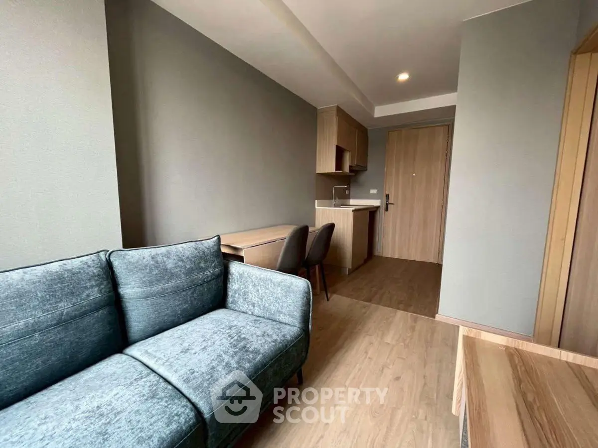 Modern living room with cozy sofa and compact kitchen in open layout apartment.
