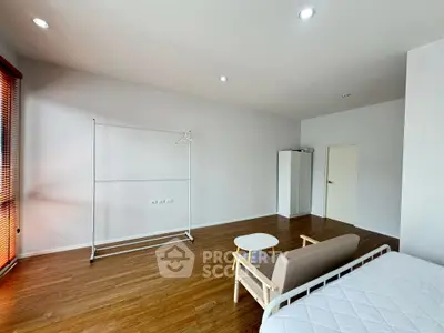 Spacious minimalist bedroom with wooden flooring and natural light