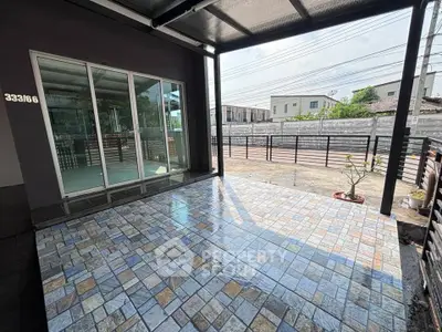 Spacious tiled patio with sliding glass doors and modern exterior design.