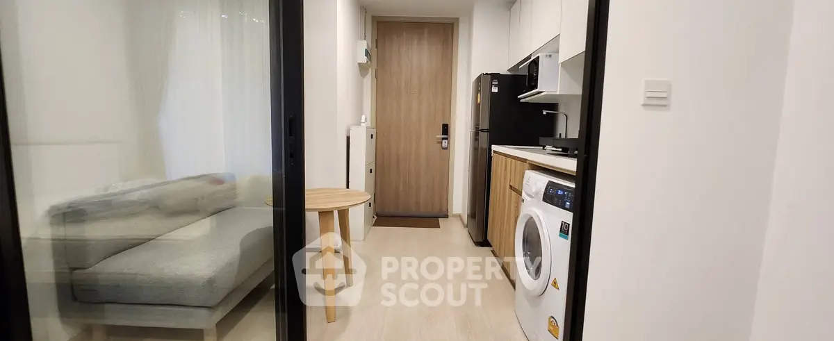 Modern apartment with compact living room and kitchen featuring washing machine and microwave.
