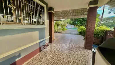 Charming outdoor patio with tiled flooring and lush garden view, perfect for relaxation and entertaining.