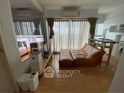 Modern living room with leather sofa, large windows, and open kitchen layout in a stylish apartment.