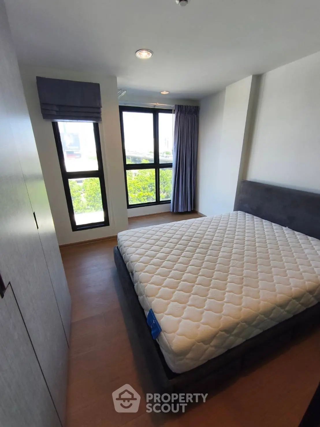 Modern bedroom with large windows and stylish decor in a cozy apartment.