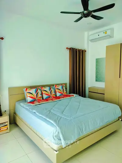 Spacious bedroom with modern decor and air conditioning, featuring a comfortable bed and stylish ceiling fan.