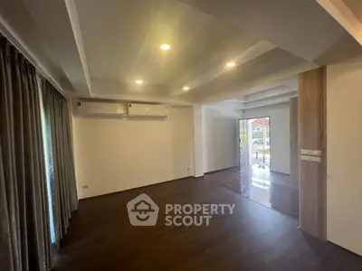 Spacious empty living room with wooden flooring and large windows
