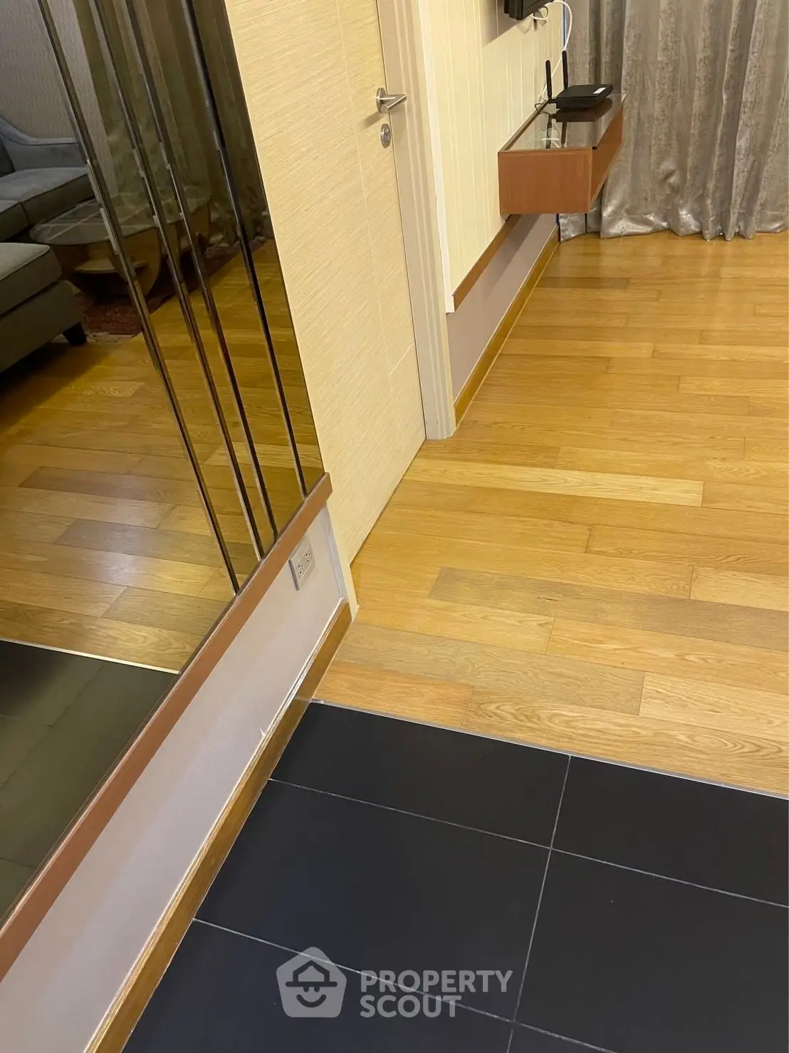 Modern interior with wooden flooring and mirrored wall, showcasing elegant design and spacious layout.