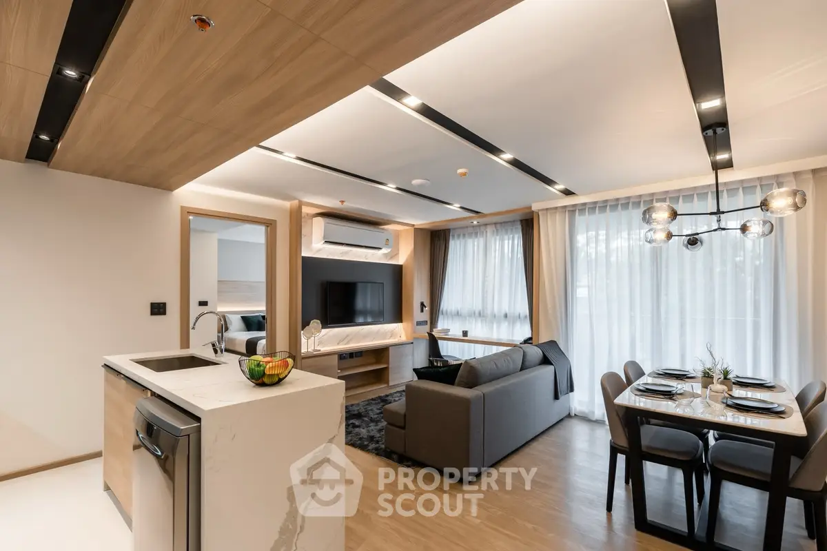 Modern open-plan living room with stylish kitchen and dining area, featuring sleek design and natural light.