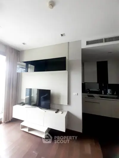 Modern living room with sleek TV unit and partial kitchen view