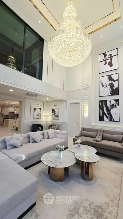 Luxurious living room with high ceiling, elegant chandelier, and modern decor