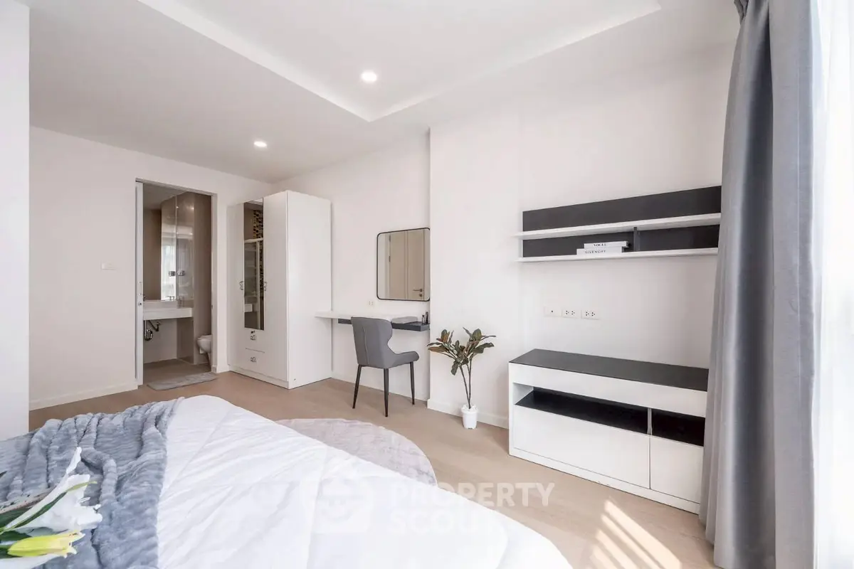 Modern bedroom with study area, featuring sleek furniture and natural light.