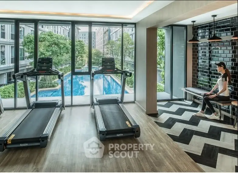 Modern gym with treadmills and pool view in luxury apartment complex.