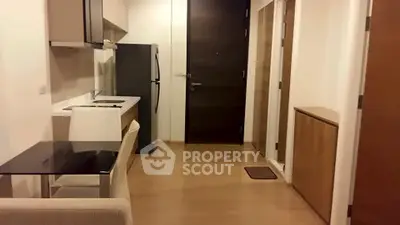 Modern compact kitchen with sleek cabinetry and dining area in a cozy apartment.