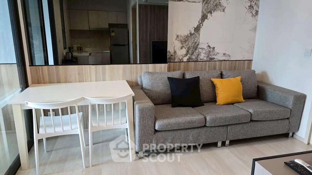 Modern living room with stylish gray sofa and dining area in open layout apartment.