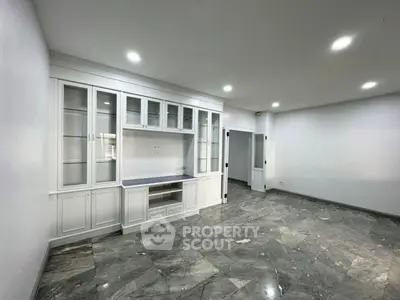 Spacious empty living room with elegant built-in cabinets and marble flooring.