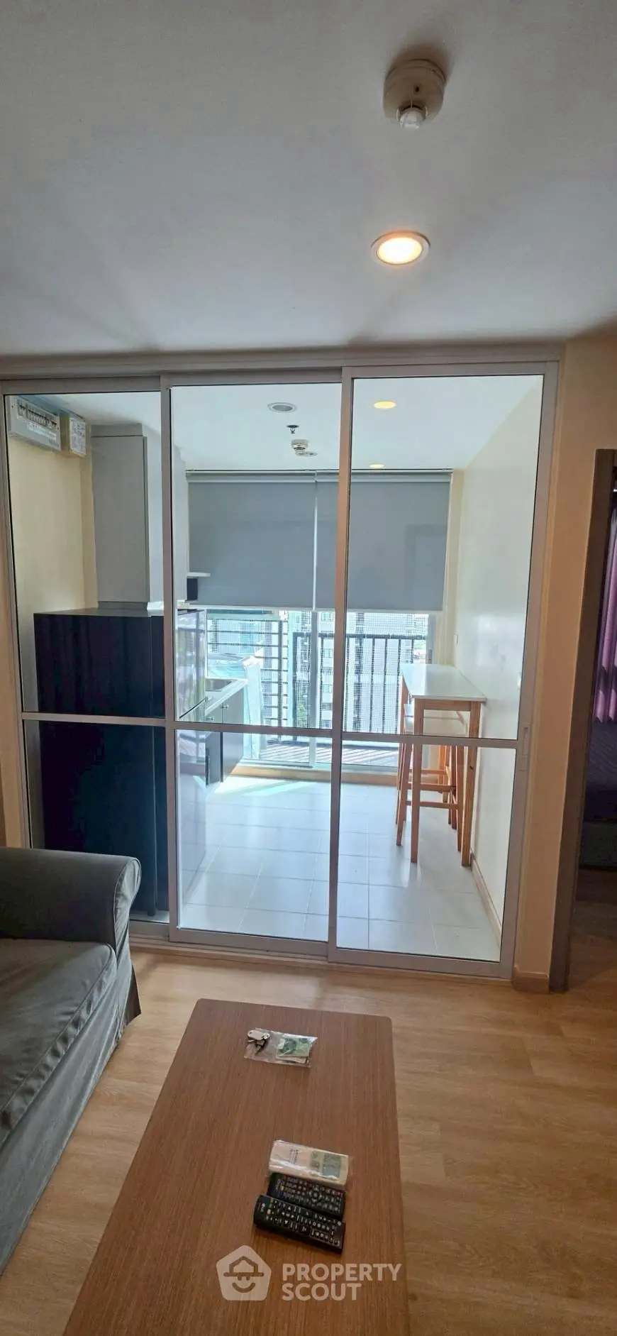 Modern living room with glass doors leading to a bright balcony with city view.