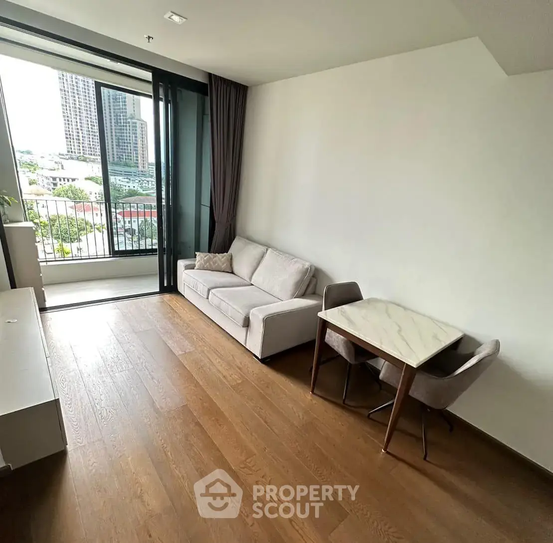 Modern living room with large windows and city view, featuring a cozy sofa and dining table.