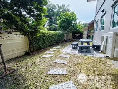 Charming garden with stone path and outdoor seating area in a serene backyard setting.