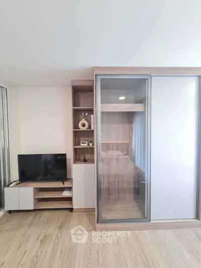 Modern bedroom with sliding glass wardrobe and TV unit on wooden flooring