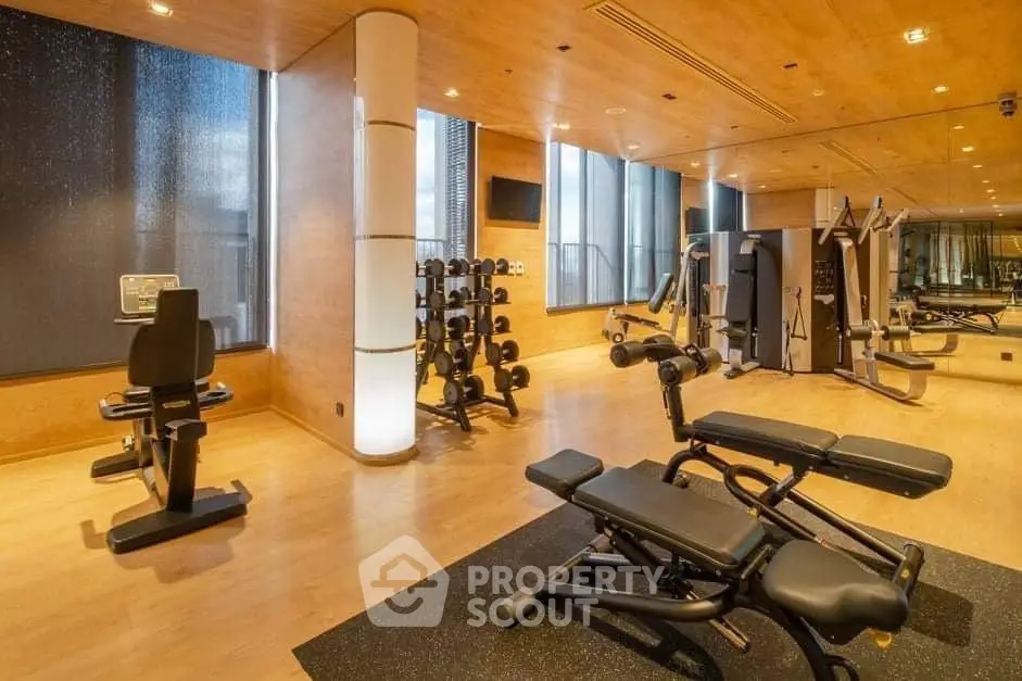 Luxurious gym with modern equipment and wooden flooring in upscale residential building.