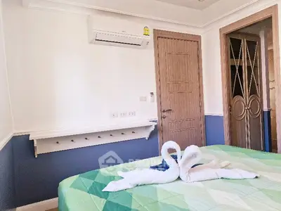 Cozy bedroom with air conditioning and stylish decor, featuring a neatly made bed with swan towel art.