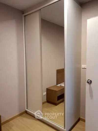 Modern bedroom with sleek mirrored wardrobe and wooden flooring