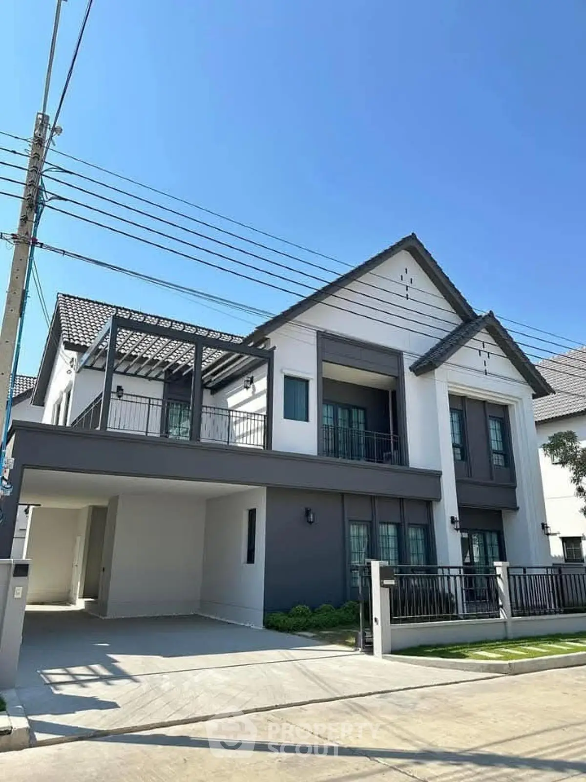 Modern two-story house with spacious driveway and elegant facade under clear blue sky.