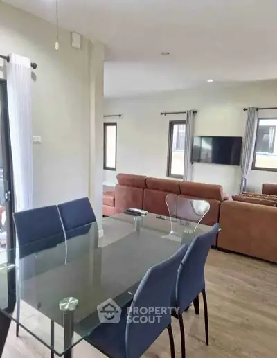 Modern living and dining area with glass table and cozy seating, perfect for family gatherings.