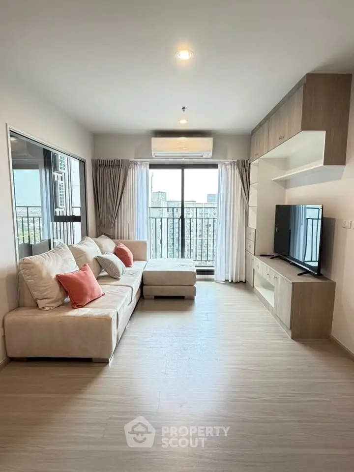 Modern living room with large windows and city view, featuring a cozy sofa and sleek entertainment unit.