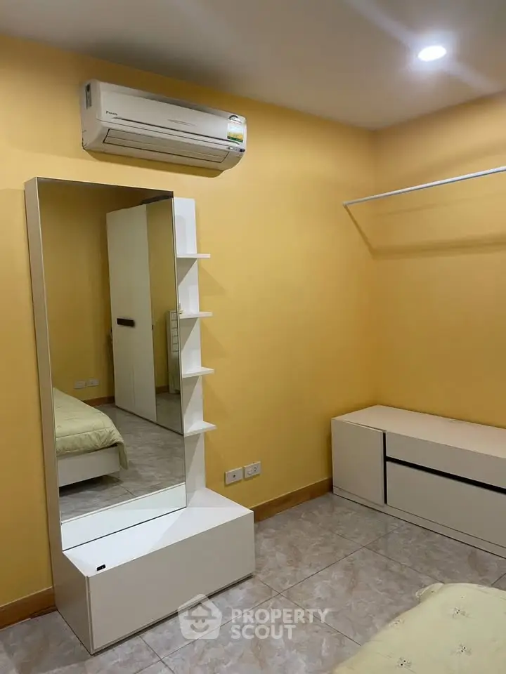 Cozy bedroom with air conditioning and modern furniture in a warm yellow ambiance.