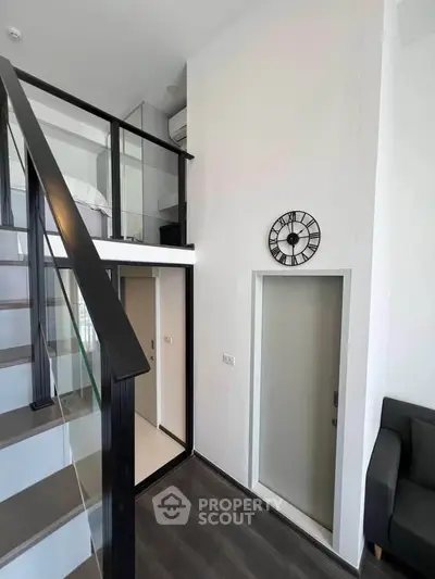 Modern loft apartment with high ceilings and stylish staircase, featuring a cozy living area and sleek design.