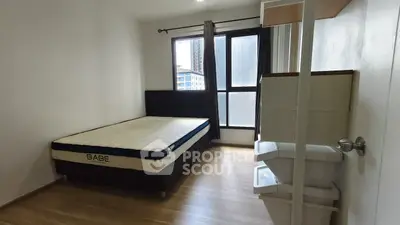 Cozy bedroom with large window and modern furnishings in urban apartment.