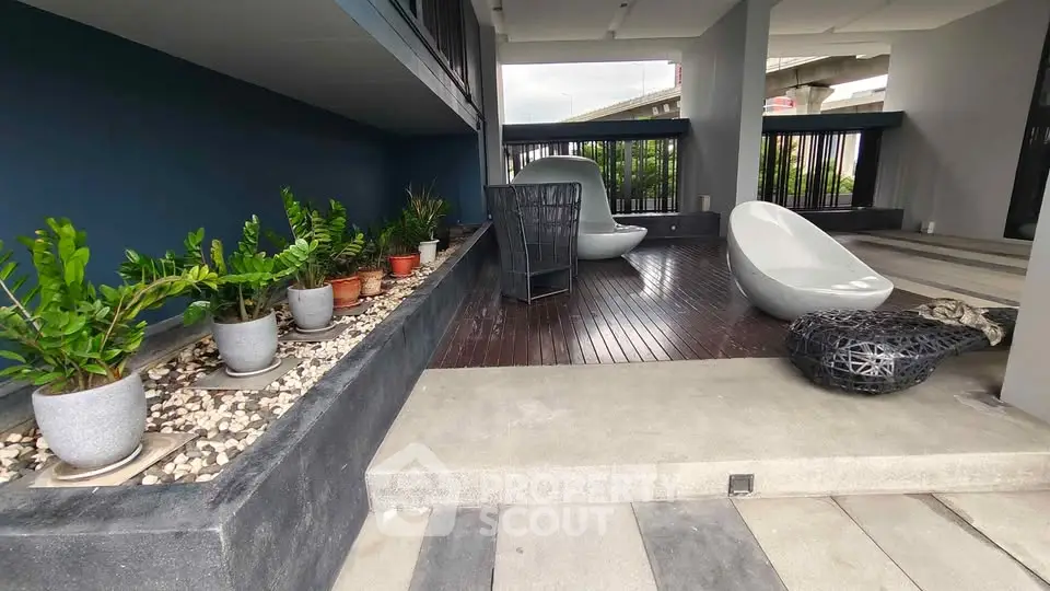 Stylish modern outdoor seating area with sleek chairs and lush potted plants, perfect for relaxation.