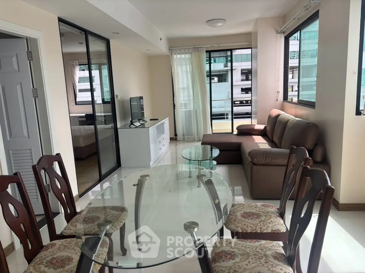Spacious living and dining area with modern furniture and large windows in a bright apartment.