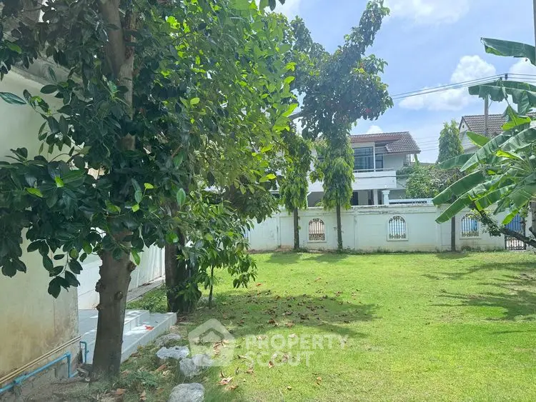 Spacious garden with lush greenery and a view of a charming residential house.
