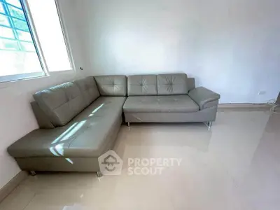 Spacious living room with modern L-shaped gray sofa and large window for natural light.