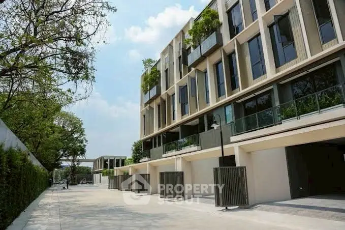 Modern townhouse complex with lush greenery and spacious balconies in a serene neighborhood.