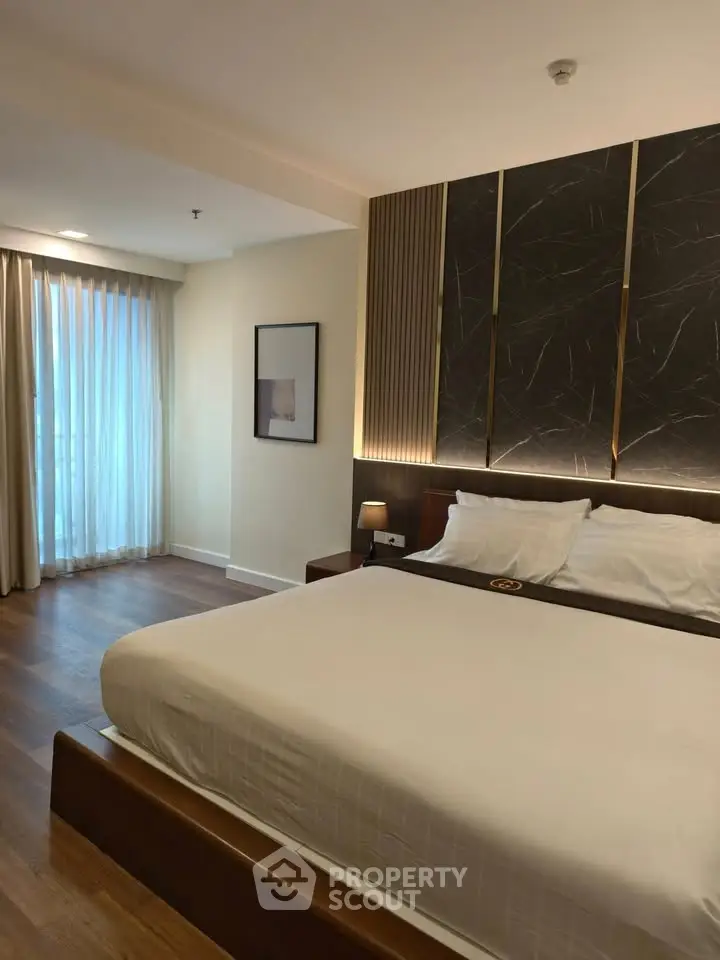 Luxurious bedroom with modern decor and large window for natural light.