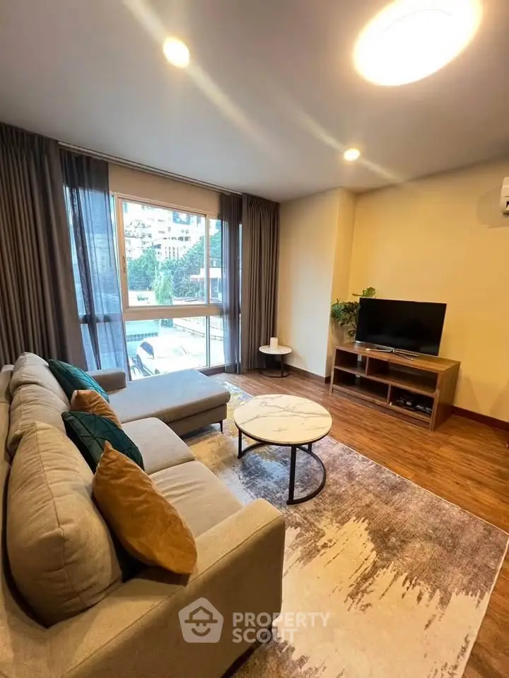 Spacious living room with modern decor and large window offering natural light.