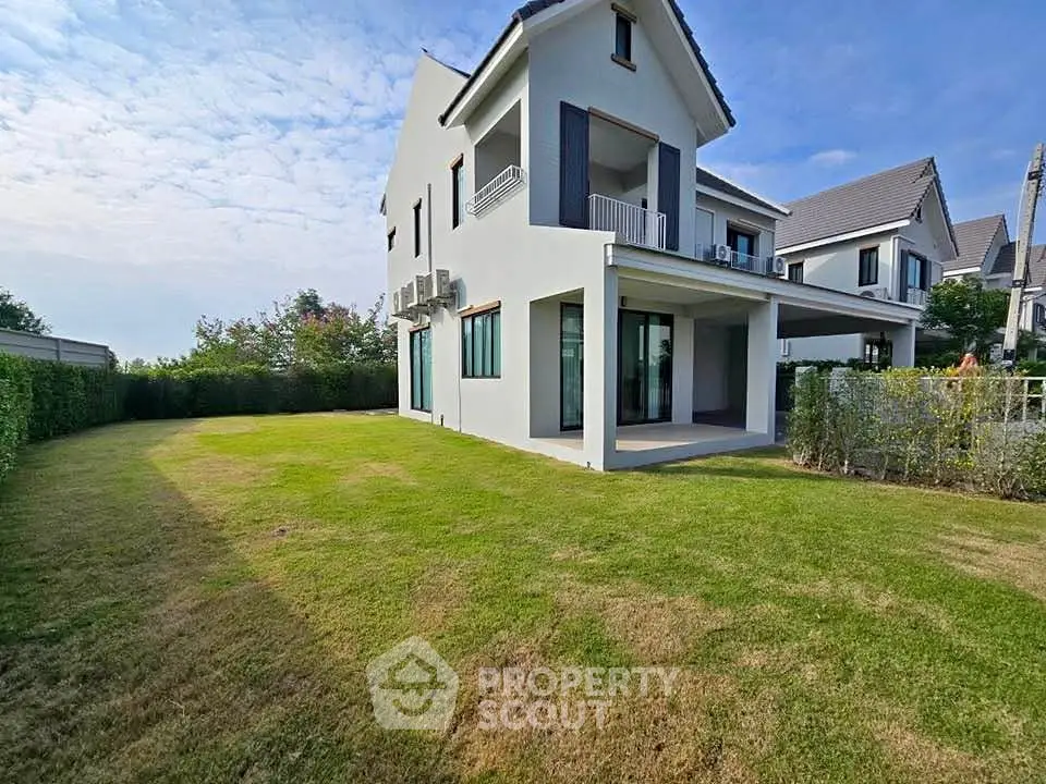 Modern two-story house with spacious green lawn and contemporary design.