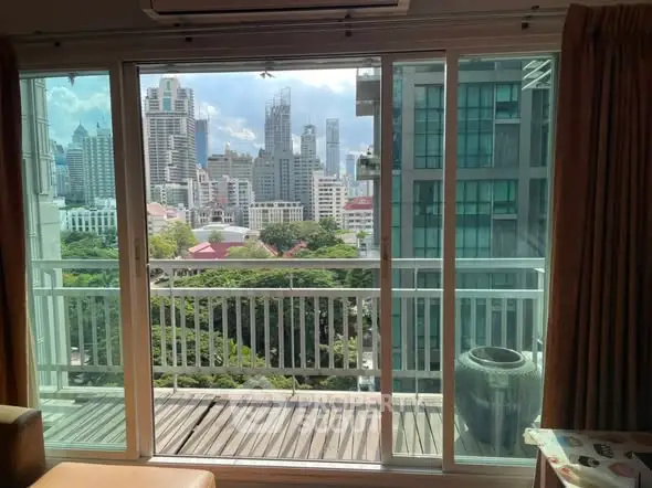 Stunning city view from modern apartment balcony with large glass doors.