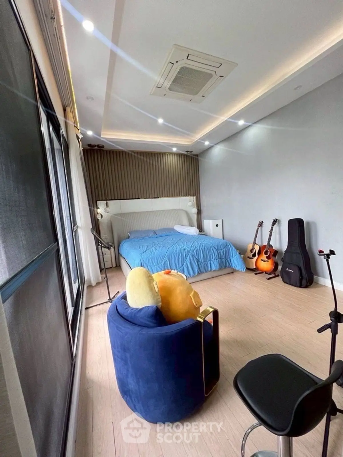 Spacious bedroom with modern decor and musical instruments, featuring a cozy blue chair.